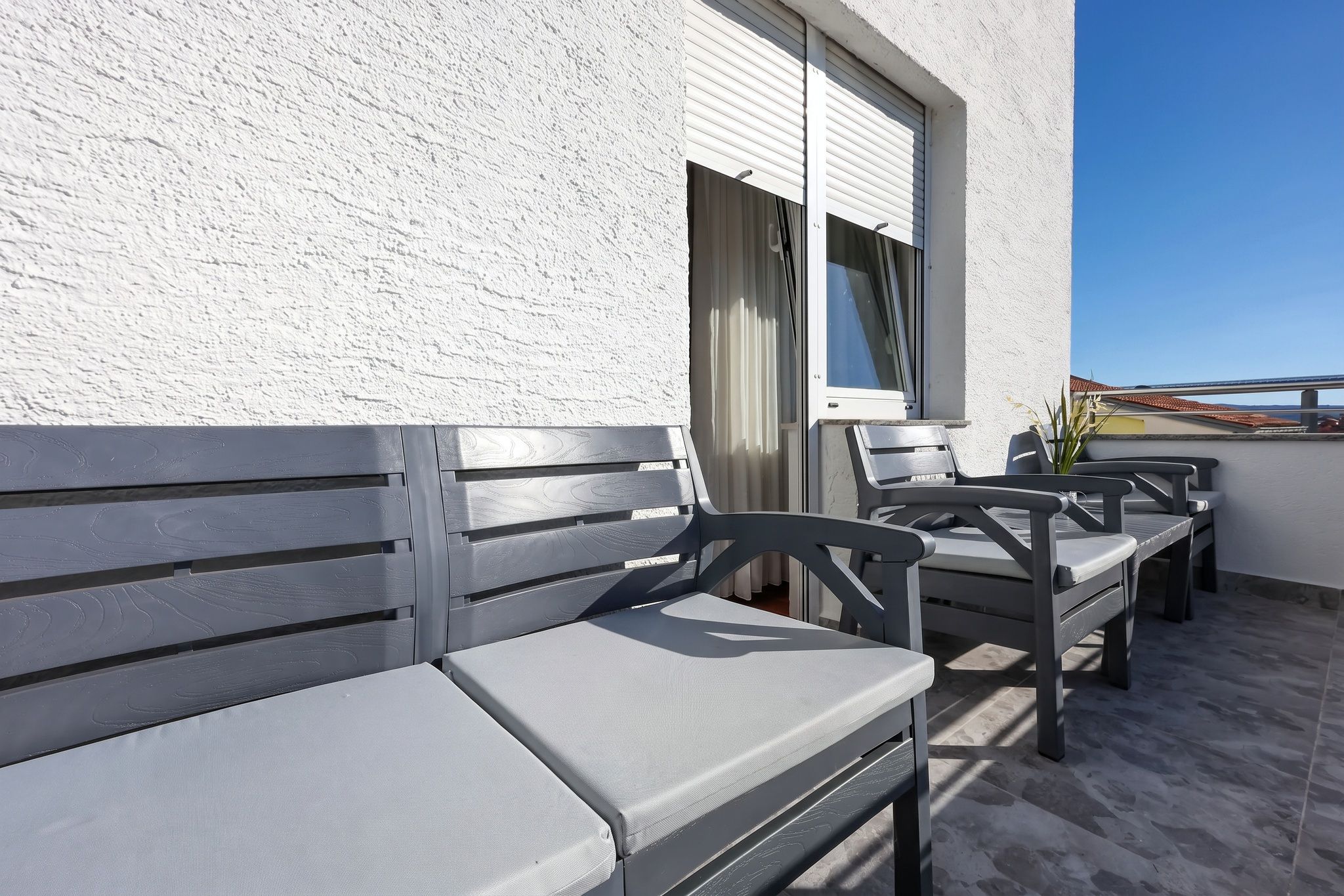 The balcony seating against the white rendered wall, the sea to the right