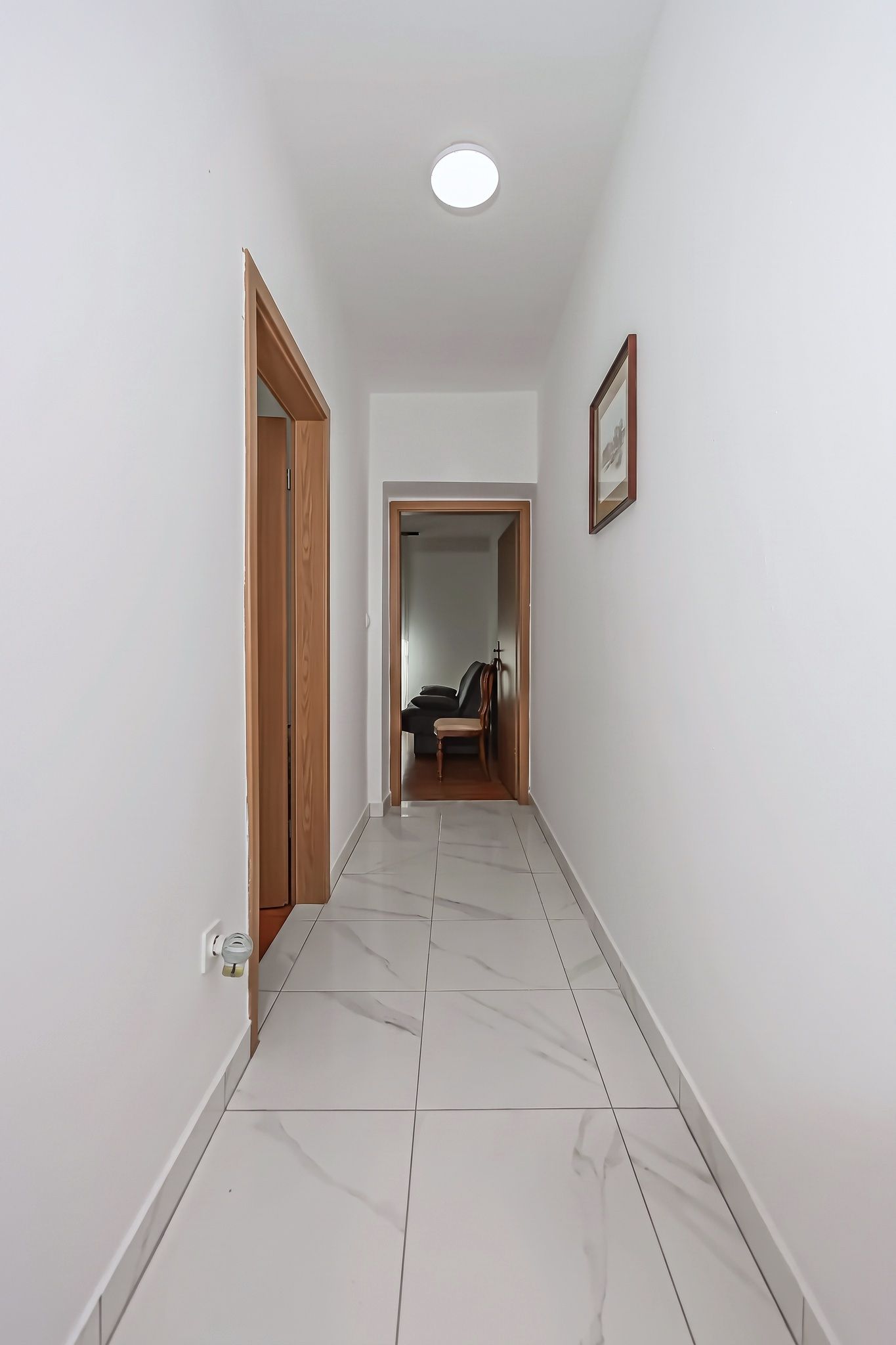 The hallway of the two-bedroom, with marble-effect floor and oak doors