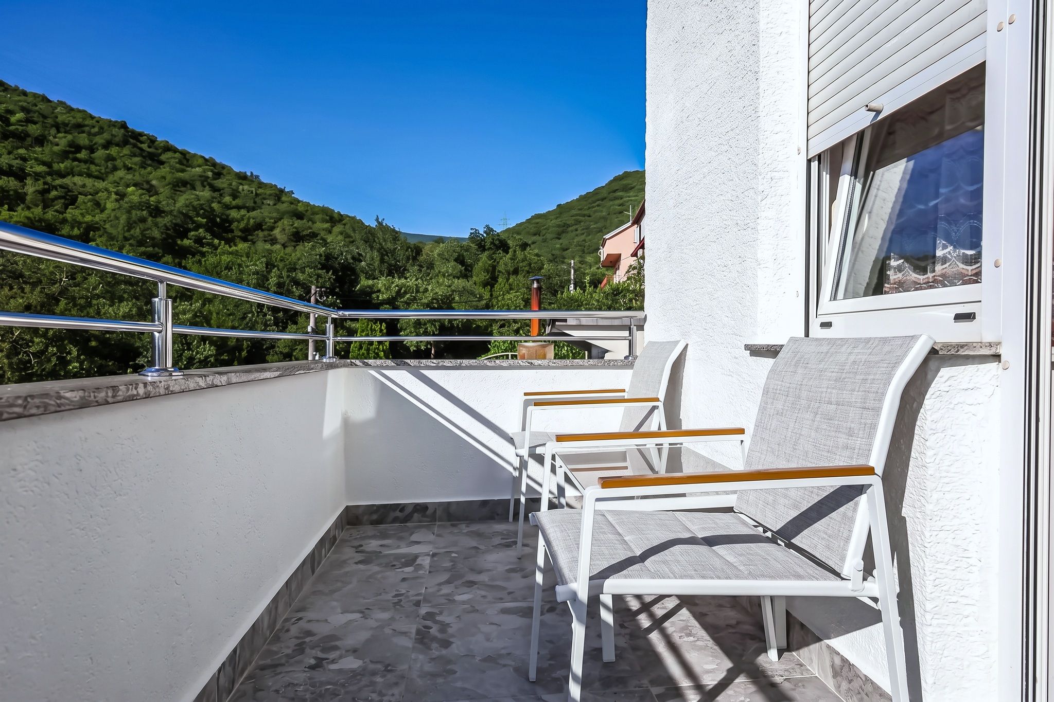 The narrow balcony of the same apartment, facing the wooded hill