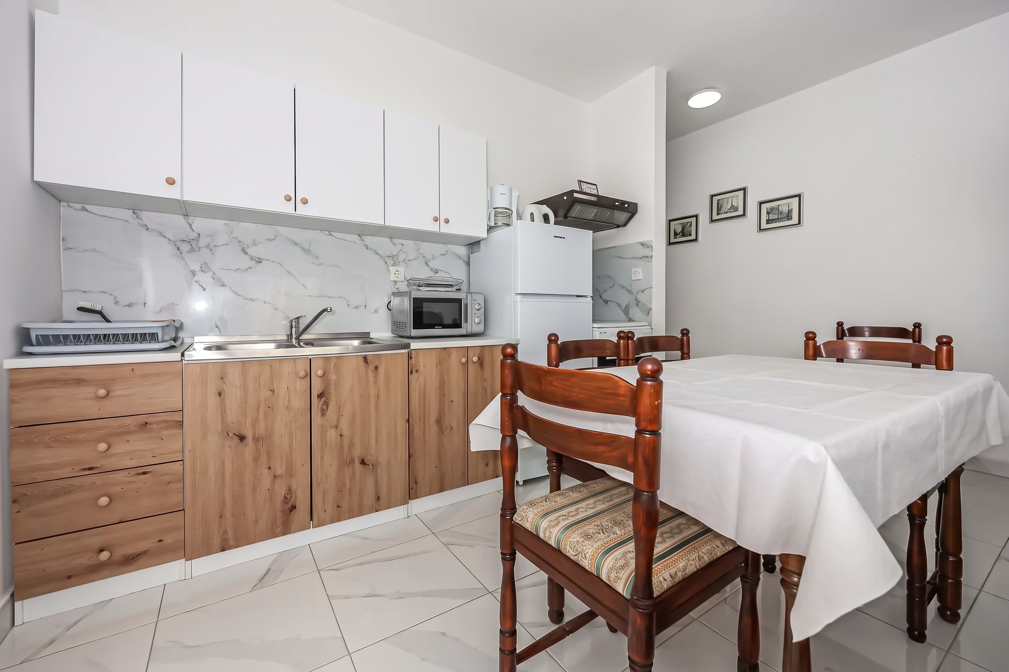 The kitchen and dining table together, with white units and an oak-fronted run