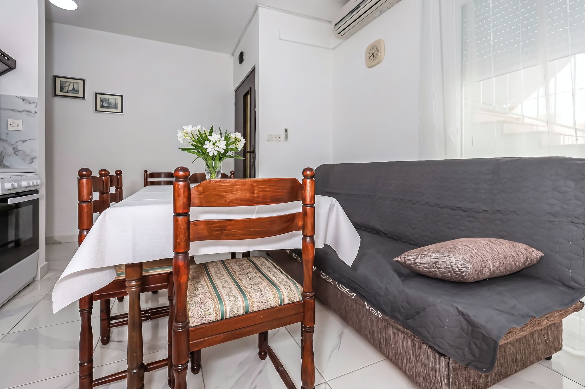 The living end of the room, with the sofa-bed, the clock and the balcony window