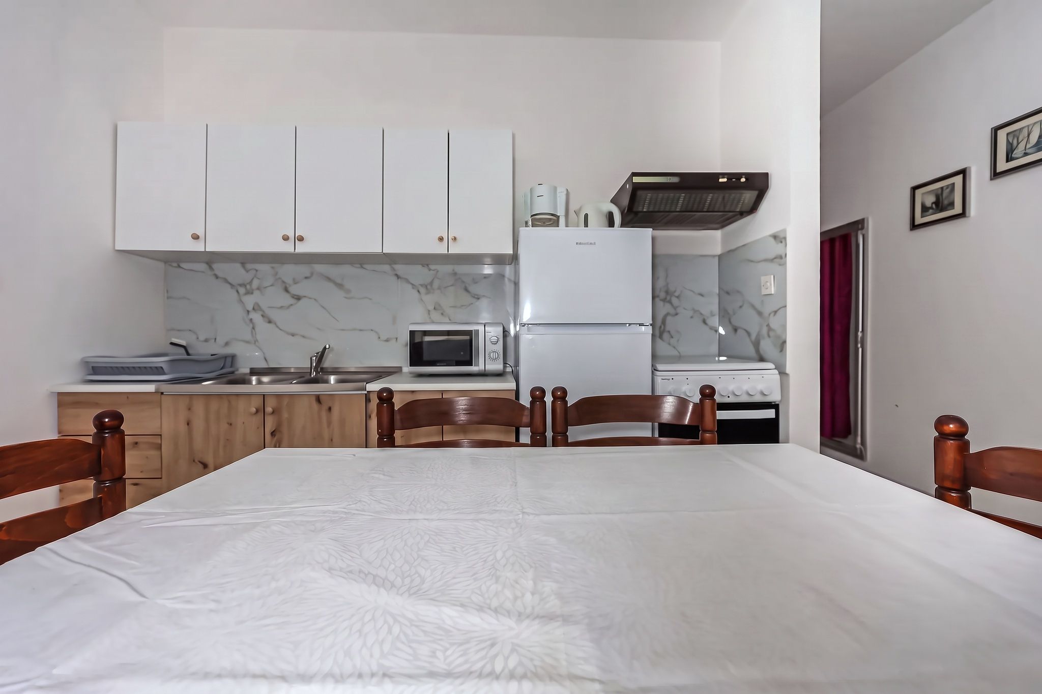 The kitchen seen across the dining table, under the extractor hood
