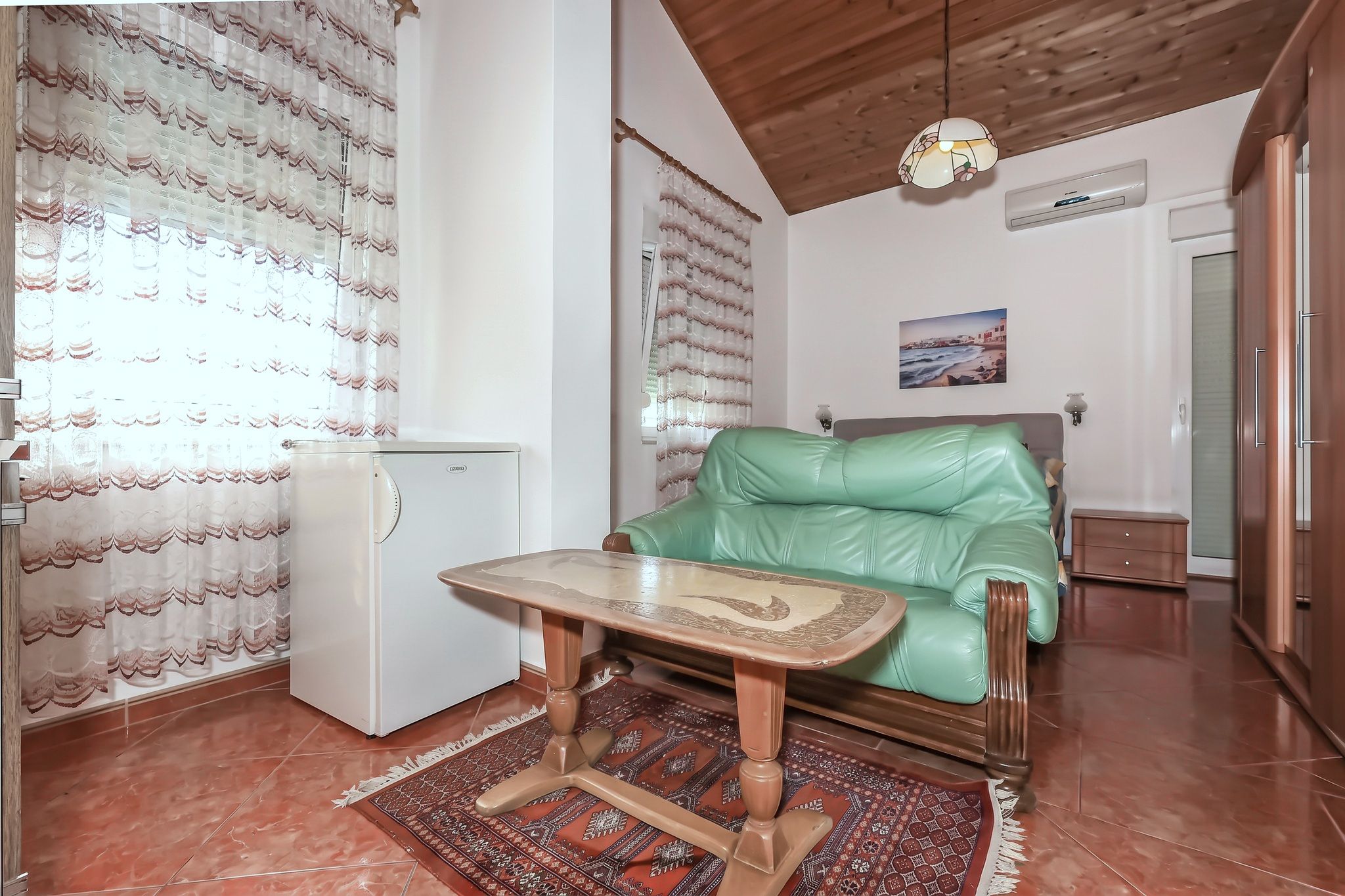 The living room, with a green leather sofa-bed and a window onto the light