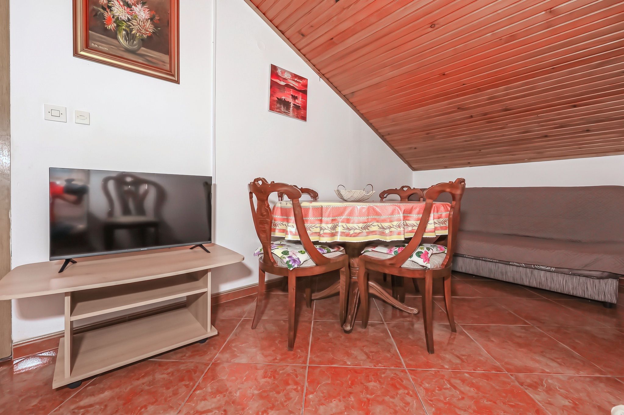 The second living and dining room, with the television and the terracotta floor