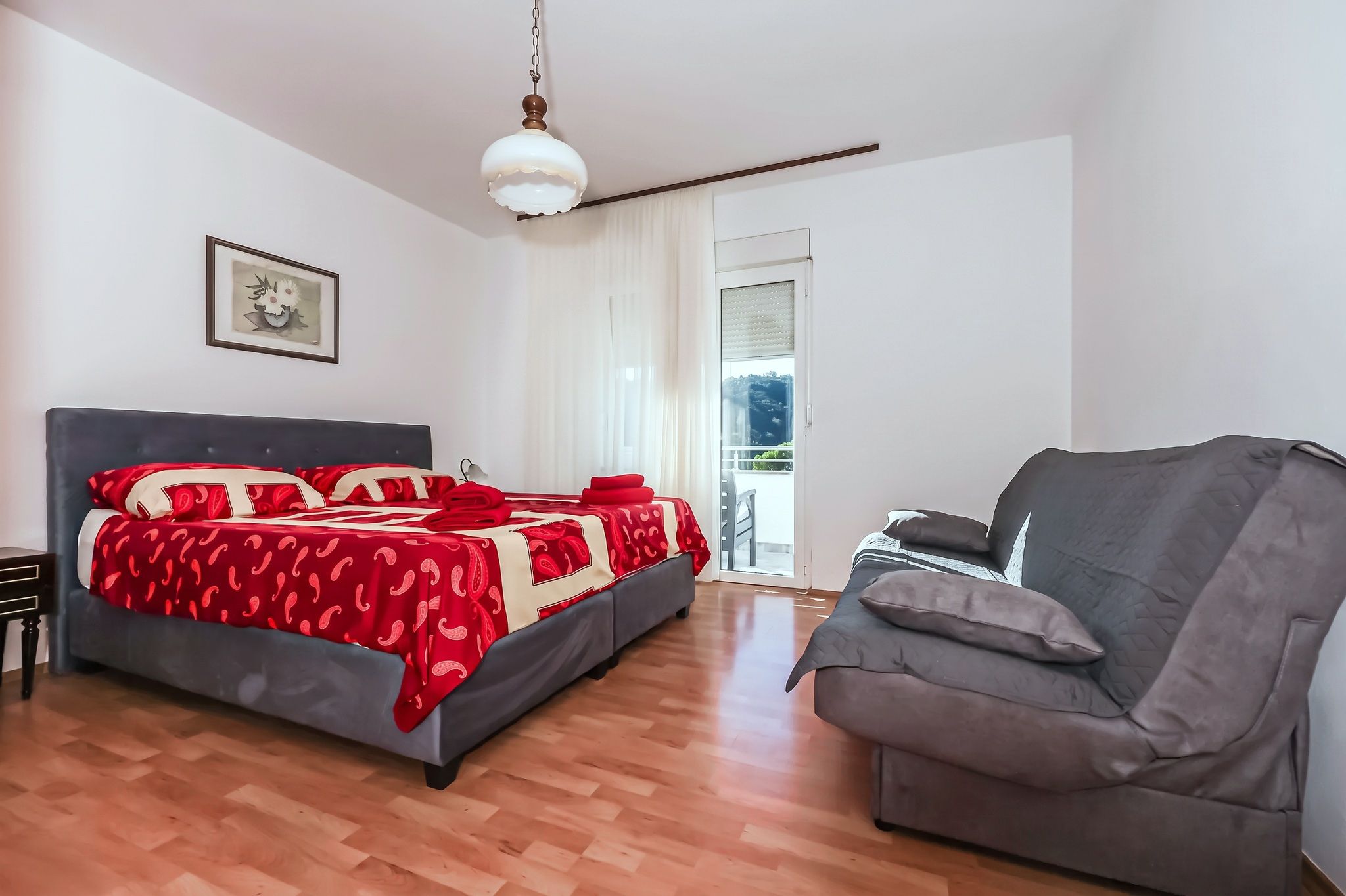 The main bedroom, with a red paisley bedspread and the balcony door behind