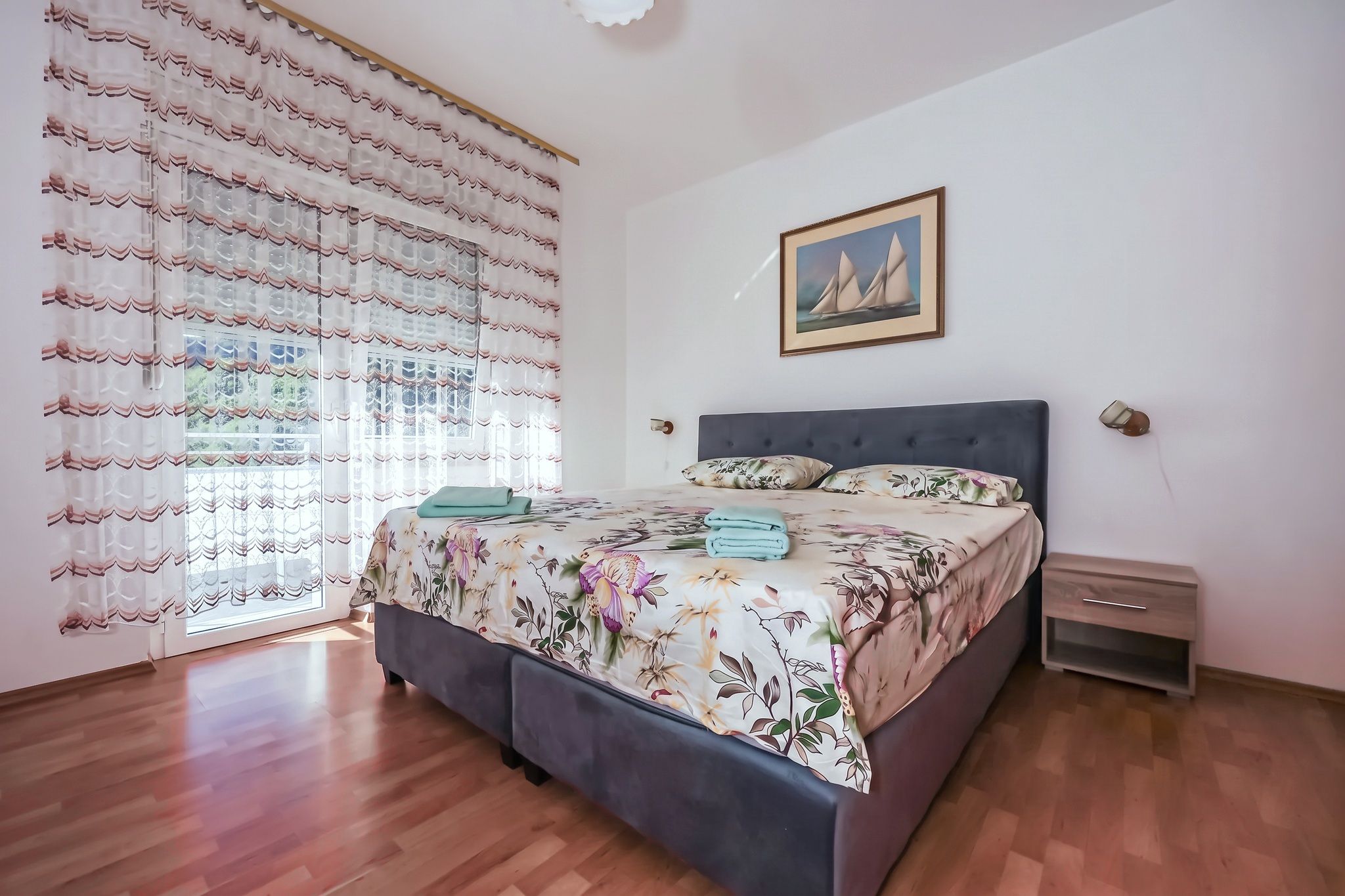 The main bedroom from the side, with the balcony window and the net curtain