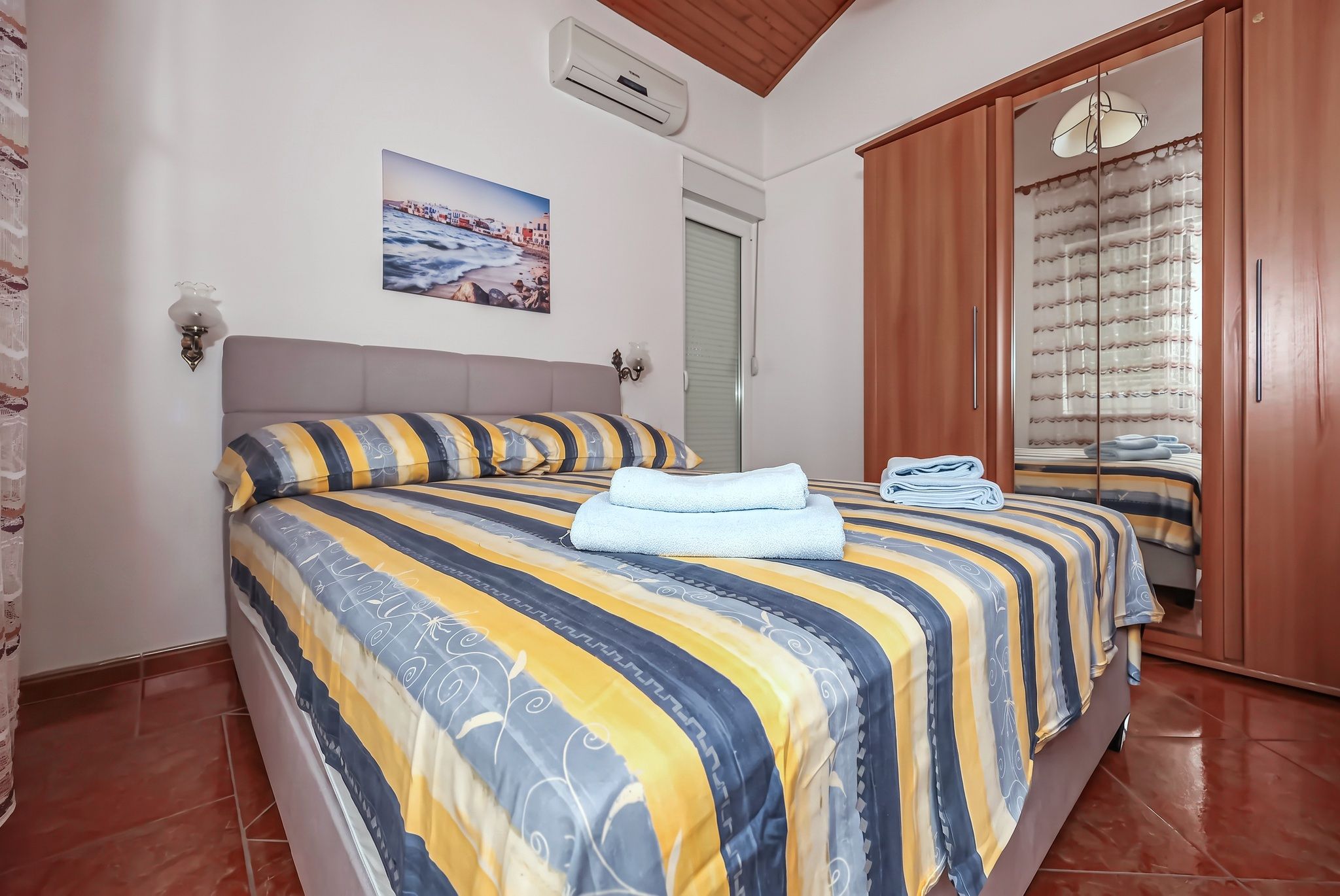 The second bedroom, with a striped bedspread and a mirrored wardrobe