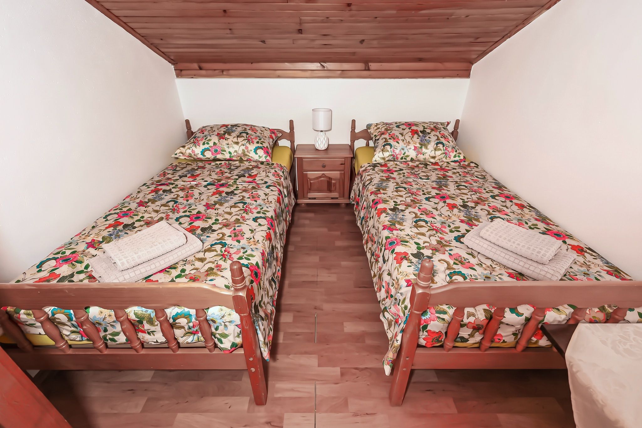 An attic twin room with two pine beds under the sloping boarded ceiling