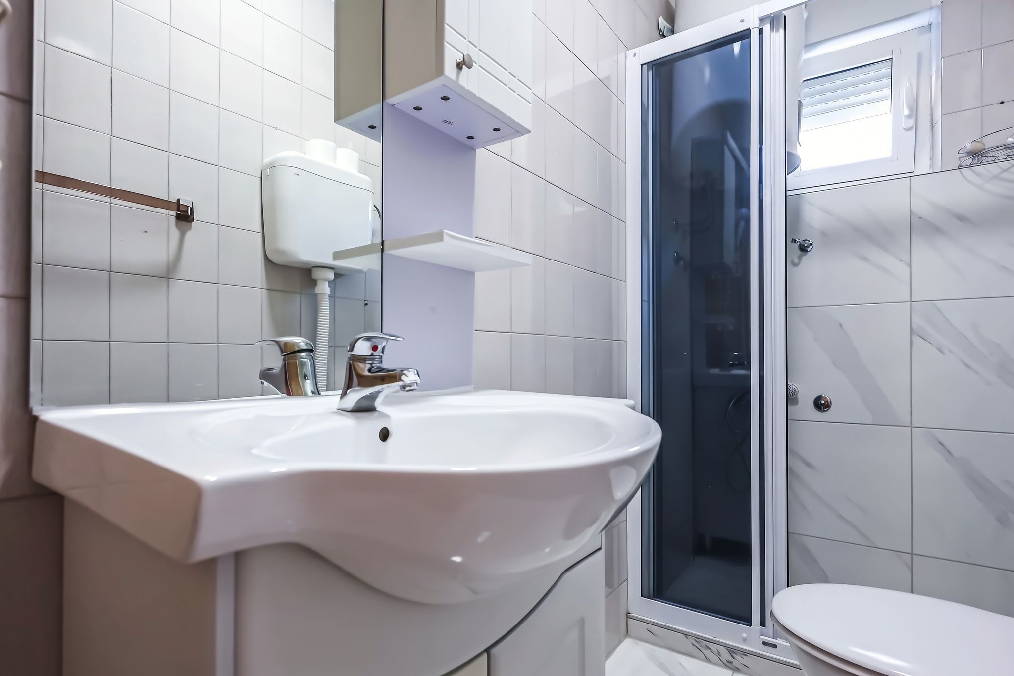 The bathroom, with a basin, mirror and a glazed shower cubicle